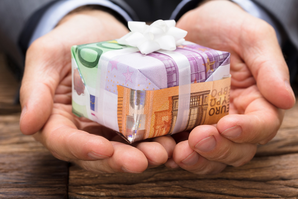 Foto: Hände bieten in Geld eingewickeltes Geschenk